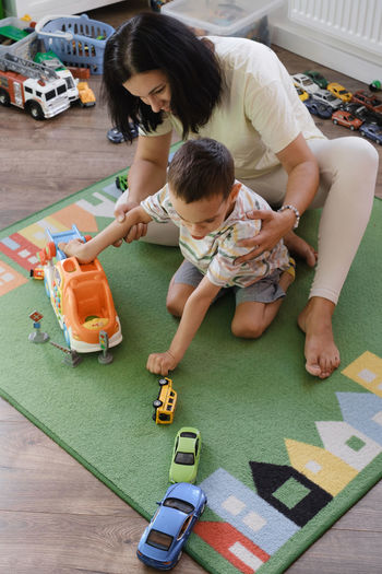 Kid with health problem playing toy cars with mother at home. child having cerebral palsy