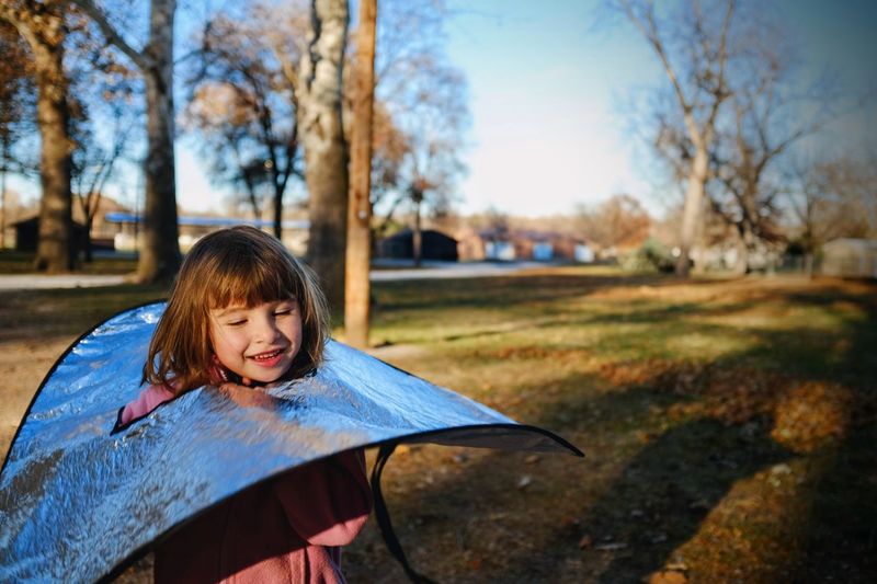 Close-up of smiling girl with reflector in park
