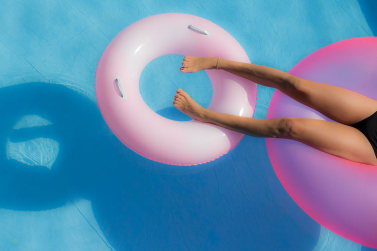 Lows section of woman relaxing on inflatable ring in swimming pool