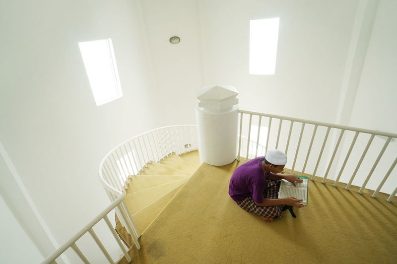 High angle view of teenage boy reading koran