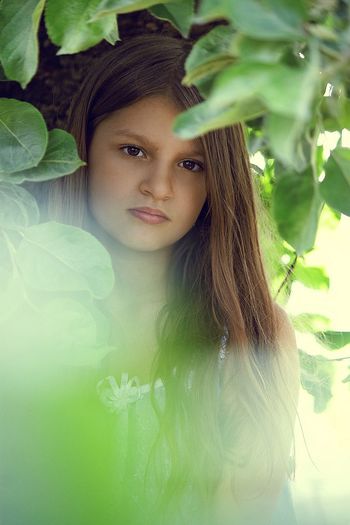 Close-up portrait of young woman standing against tree