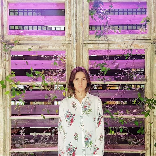 Portrait of woman standing against purple flowering plants