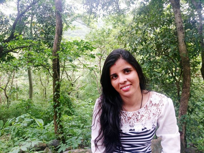 Portrait of smiling young woman sitting in forest