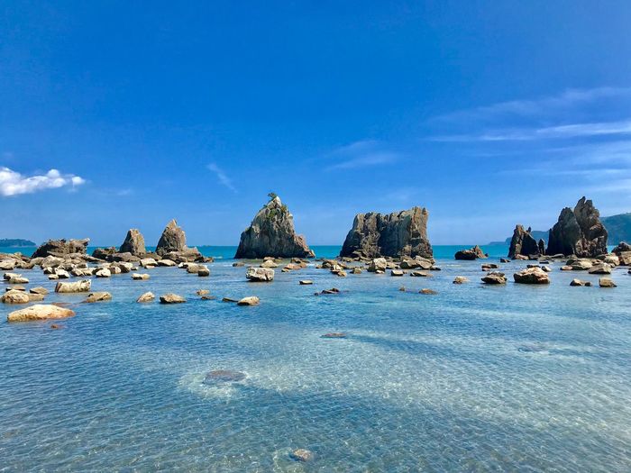 Panoramic view of rocks on beach against blue sky