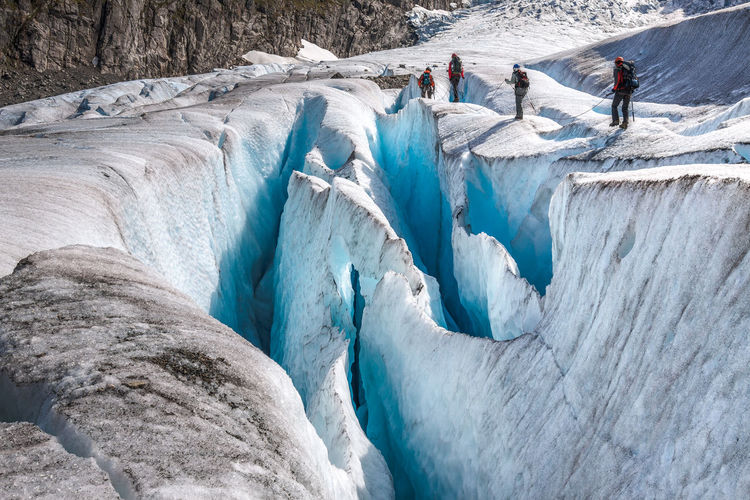 Rear view of people hiking on glacier