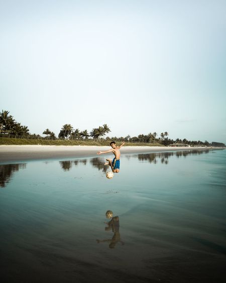 Reflection of woman in lake against clear sky