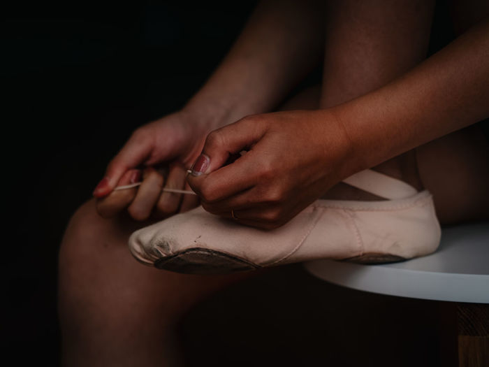 Female ballerina tying her pointe shoes