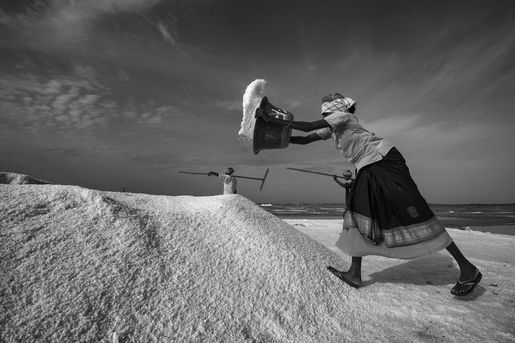 Woman working at salt flat against sky