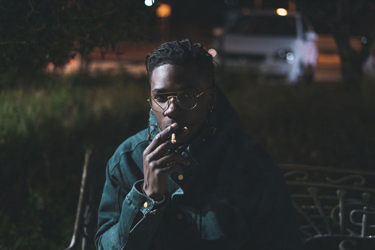 Portrait of young man smoking marijuana joint at night