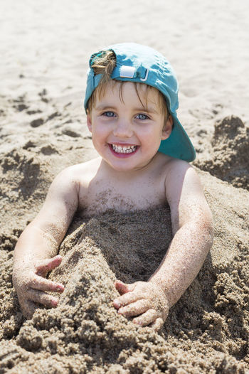 Happy boy buried in sand