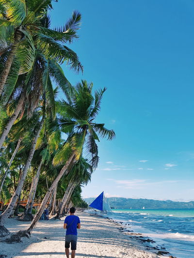 Man standing on beach against clear blue sky