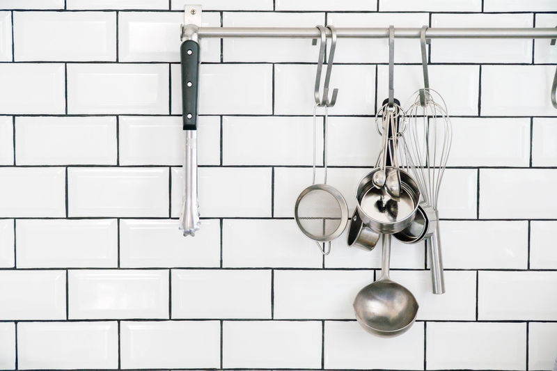 Kitchen utensils hanging against white wall