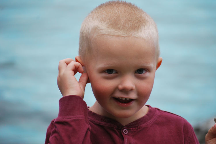 Portrait of cute boy smiling against sea