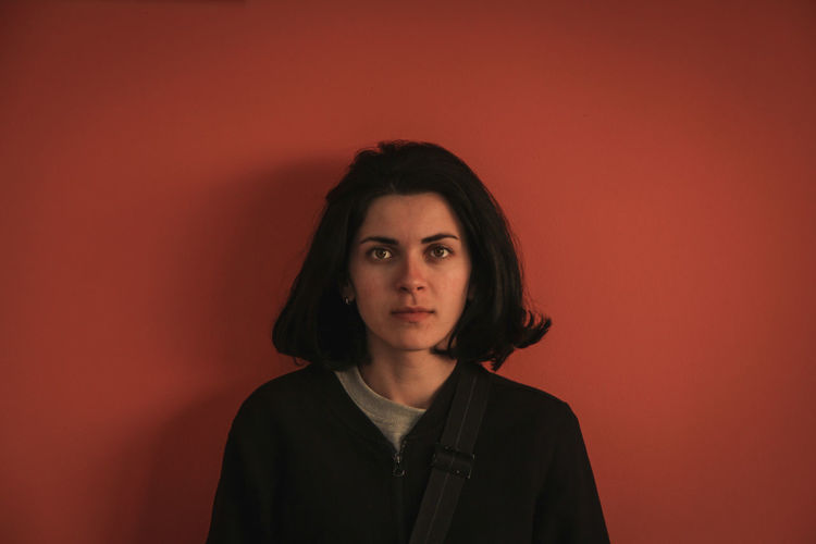 Portrait of young woman against orange background