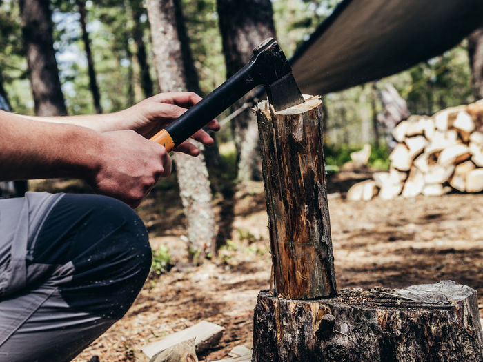 Midsection of man cutting wood in forest
