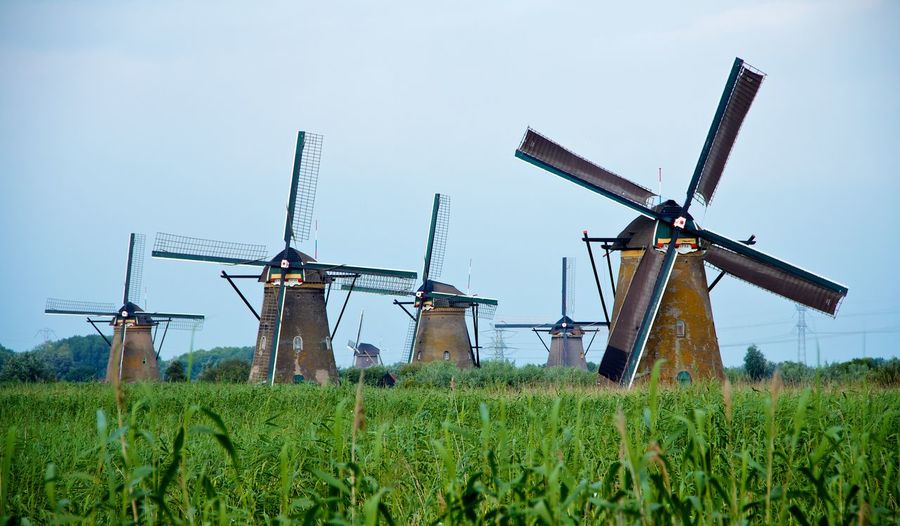 Traditional windmills on field against sky
