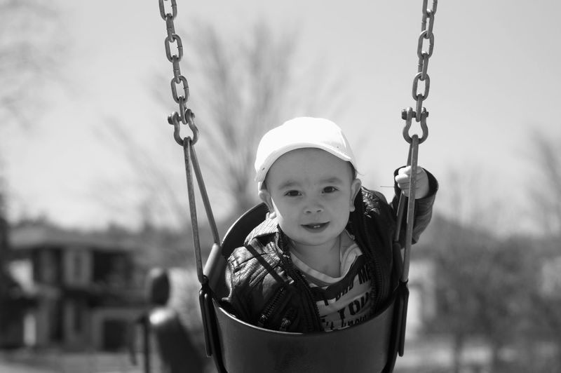 Portrait of cute baby boy swinging at playground
