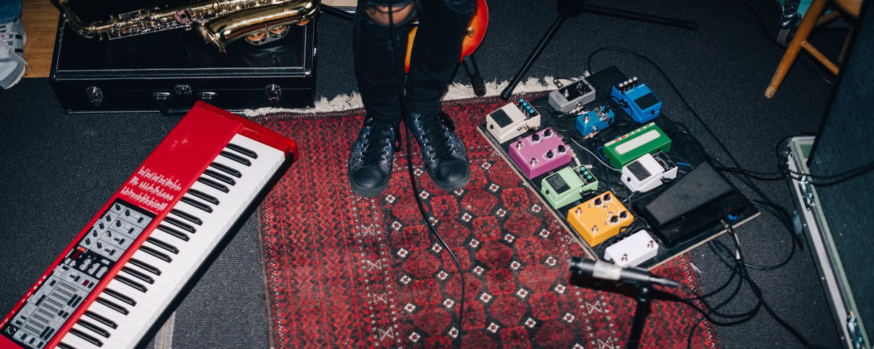 Low section of musician standing by musical instruments on floor at studio