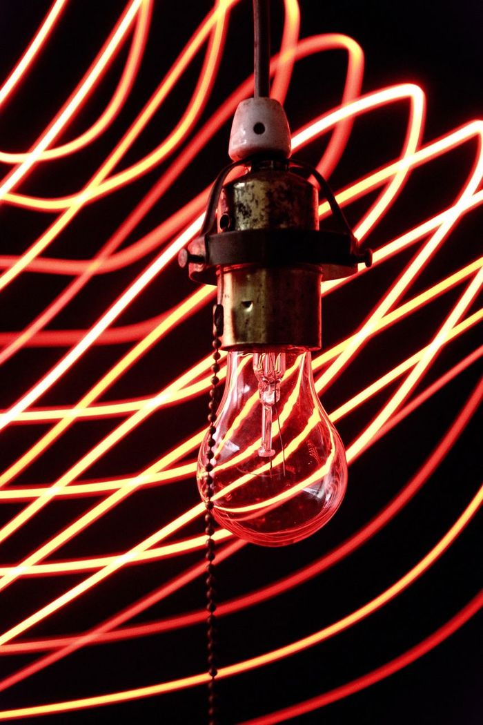 Close-up of electric bulb by light trails against black background