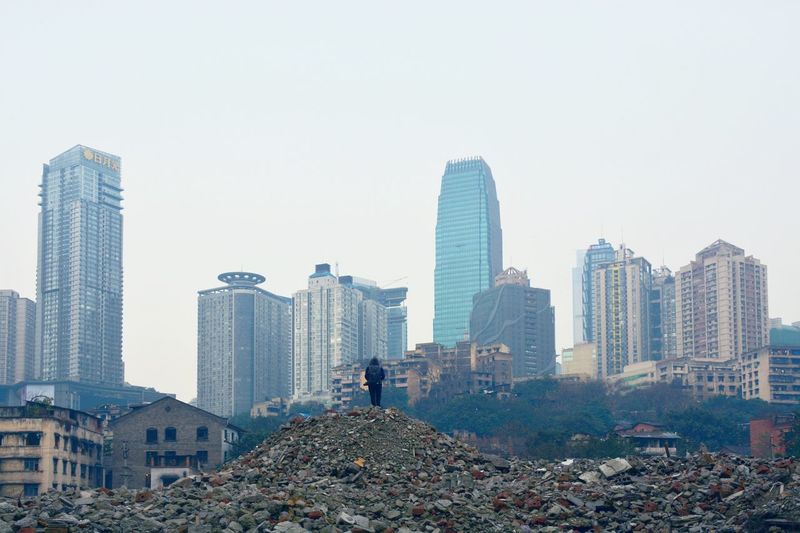 Low angle view of person standing at demolished area against sky in city