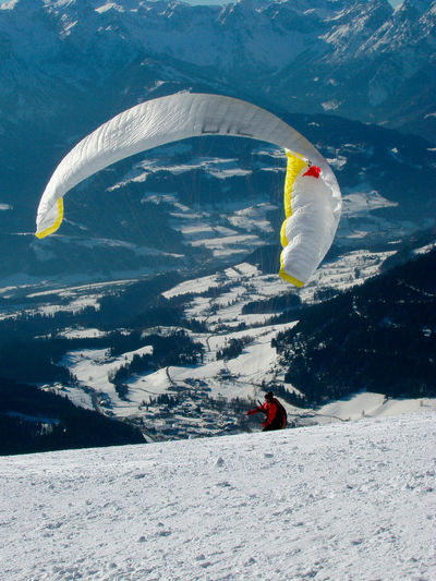 Person paragliding on snowy mountain