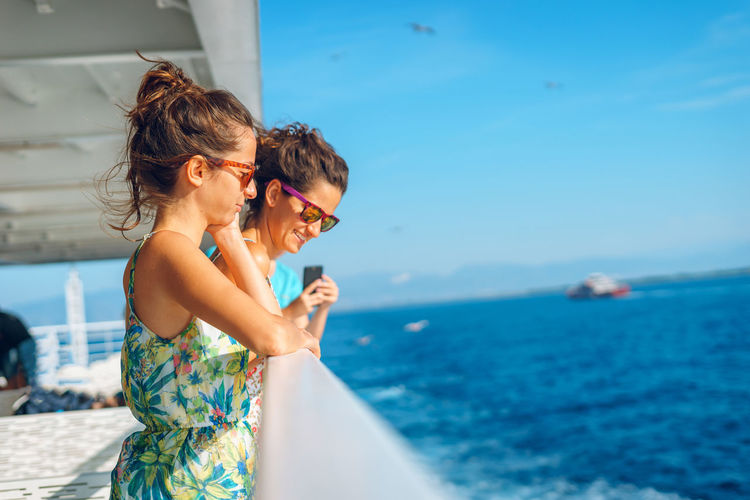 Friends standing by railing on nautical vessel