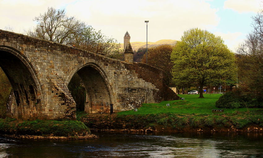 Arch bridge over river against sky