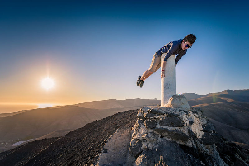 Man performing stunt on mountain against sky