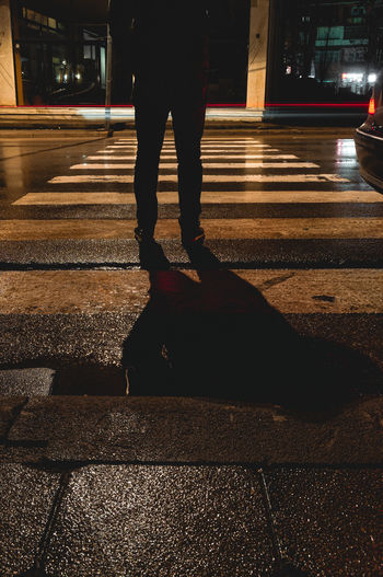 Low section of man walking on road at night