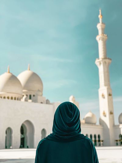 Rear view of woman looking at mosque against sky