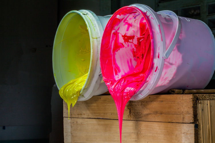 Close-up of paints dripping from buckets on wooden container