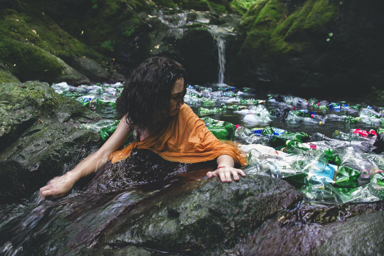 Woman amidst plastic bottles in water