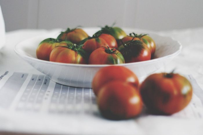 Tomatoes lying on white plate and on table