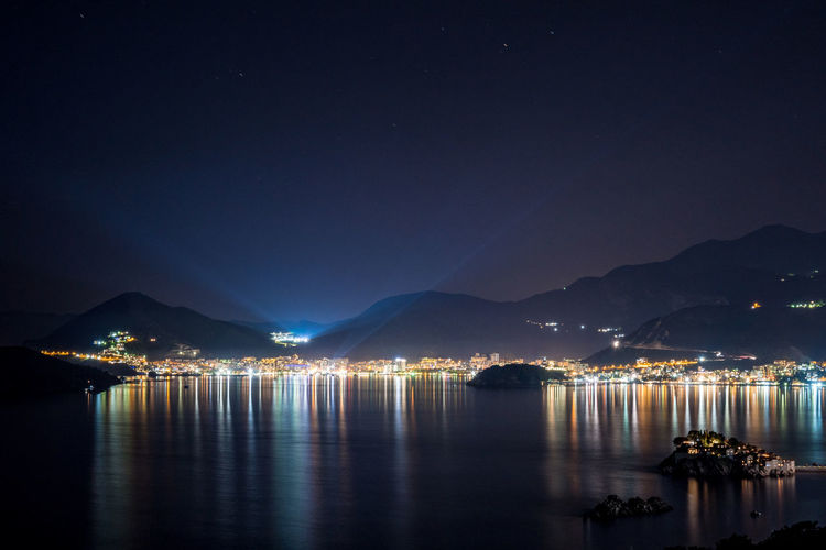 Scenic view of illuminated sea against sky at night