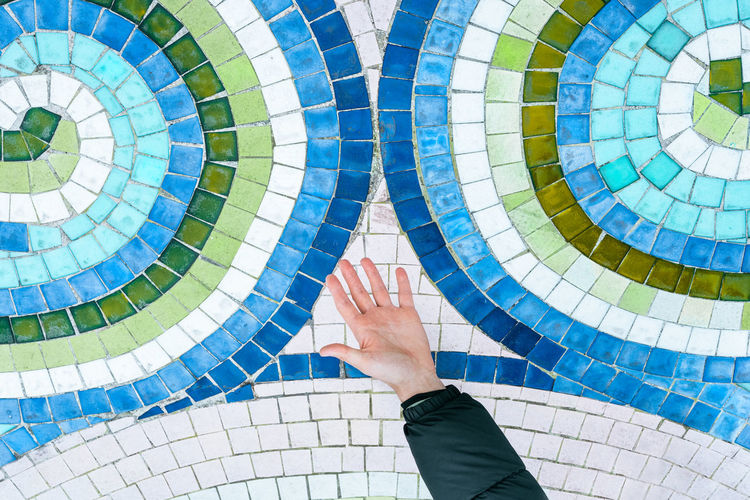 Cropped hand of man by colorful mosaic
