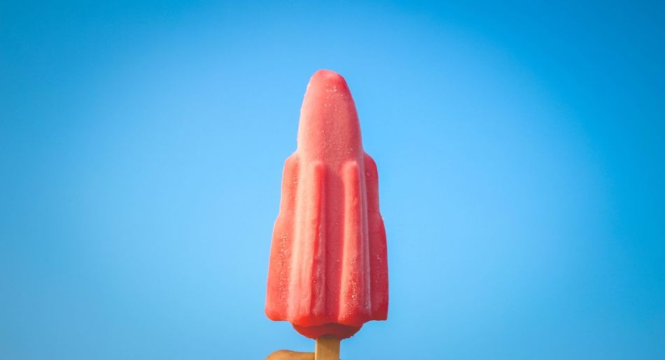Close-up of pink popsicle against blue background