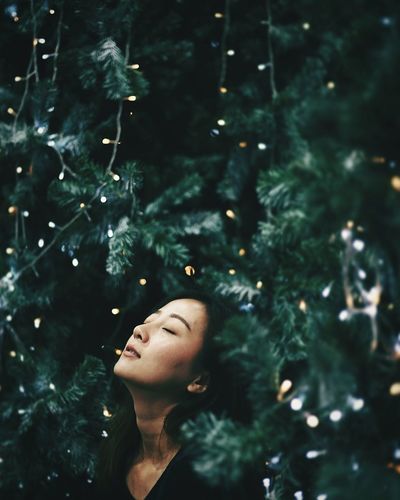 Close-up of young woman against christmas tree