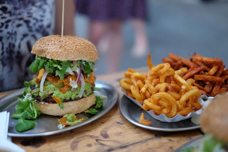 Close-up of burger with onion rings and french fries in plate on table