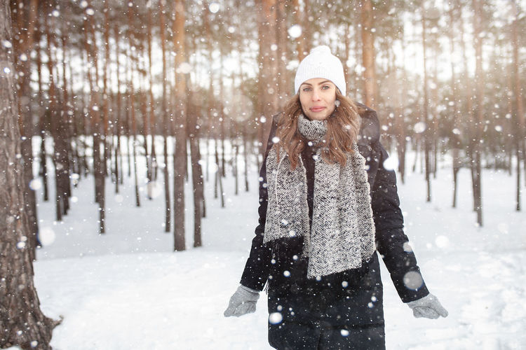 Side view portrait of confident woman standing in snow covered forest