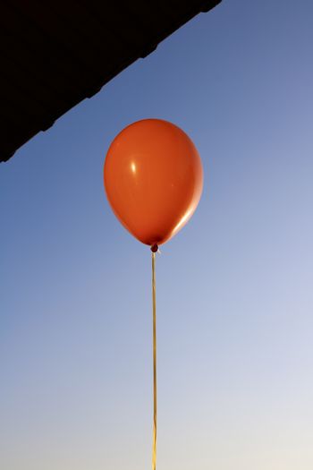 Low angle view of red balloon against clear blue sky