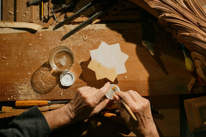 The hands of a carpenter's craftsman painting a wooden star, unrecognisable.