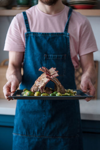 Roasted rack of lamb on a tray in the hands of the chef. barbecue season