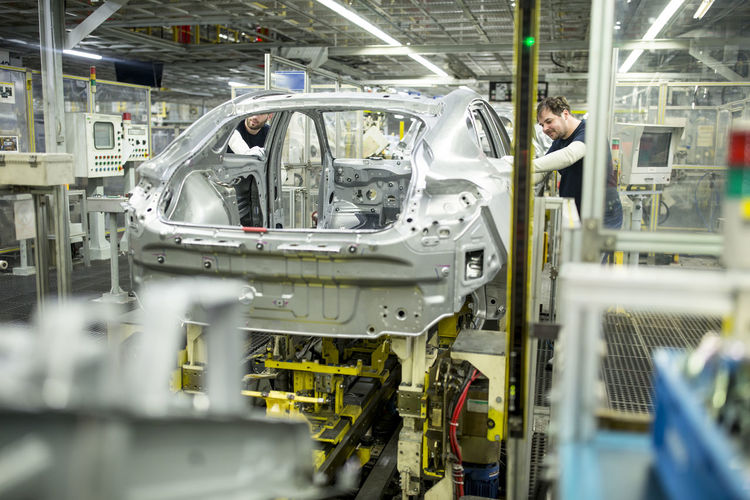 Two colleagues working in modern car factory