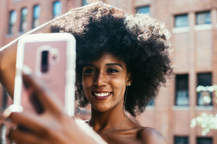 PORTRAIT OF SMILING WOMAN USING MOBILE PHONE