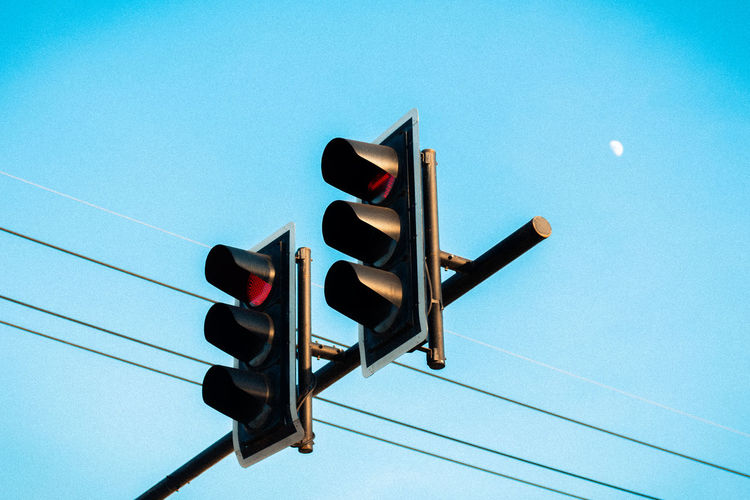 Low angle view of traffic signal against clear blue sky