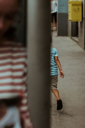 Rear view of boy walking on street in city