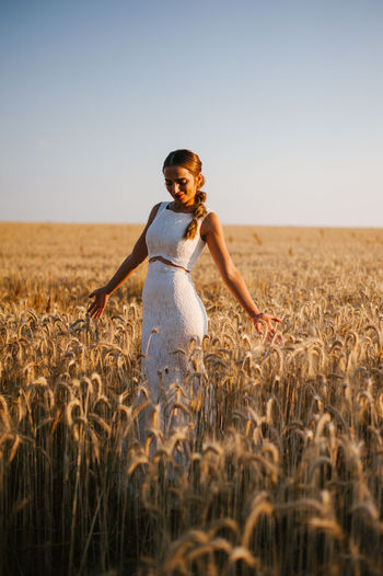 Bride standing amidst cereal plants on agricultural field