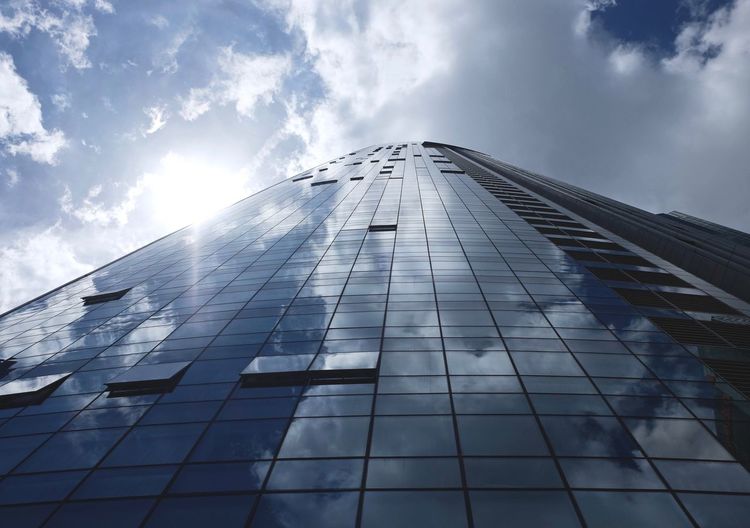 Low angle view of modern building against cloudy sky