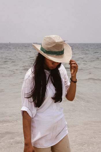 Woman wearing hat while standing on beach