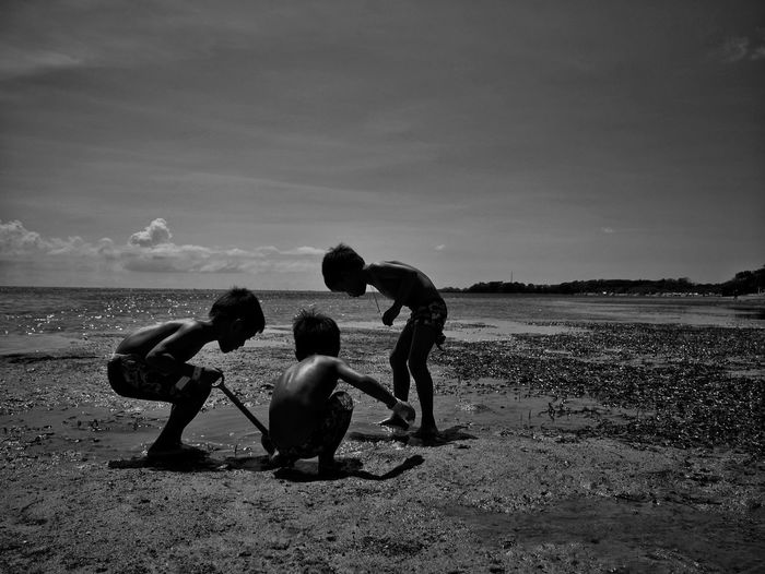 Children playing on beach against sky